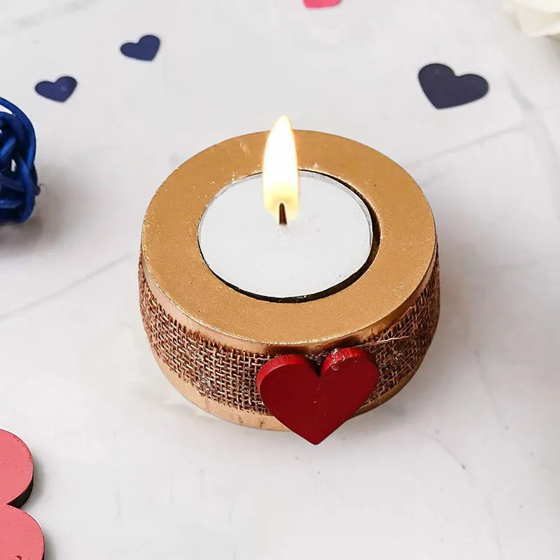 Close-up of a round gold-toned tea light holder with a red heart accent