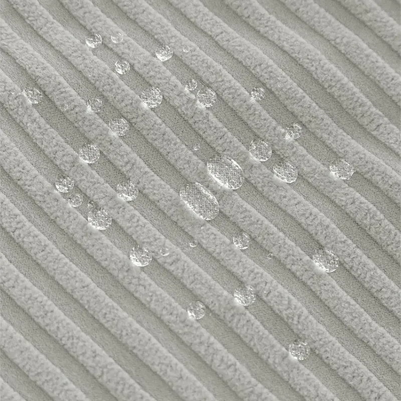 Close-up of water droplets on grey textured chair cover fabric