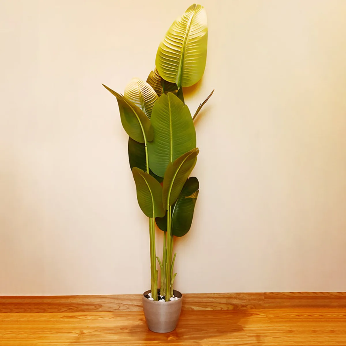 Artificial Bird of Paradise plant with green leaves in a black pot indoors
