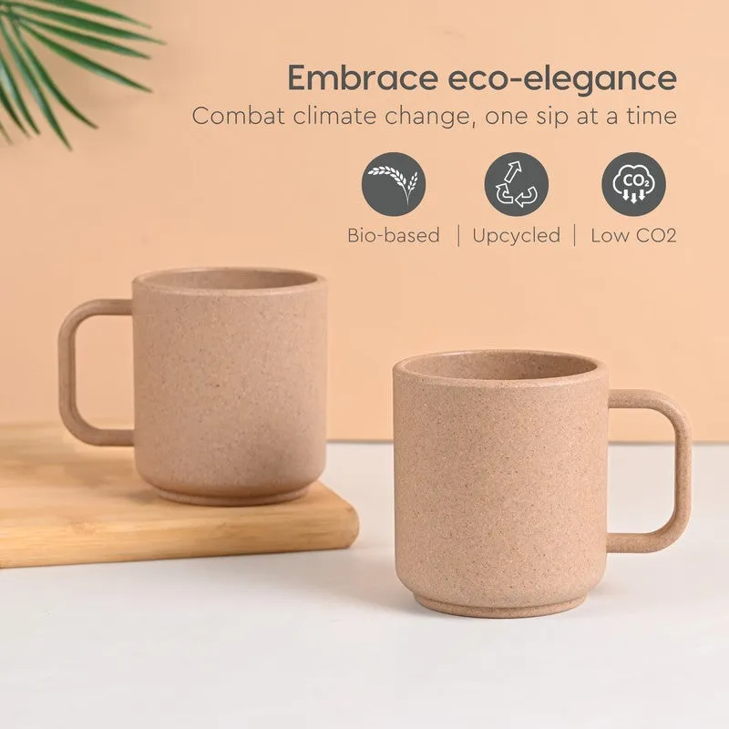 Two earthy brown mugs styled against a peach backdrop