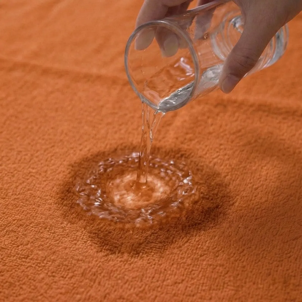 Water being poured onto an orange towel fabric close-up