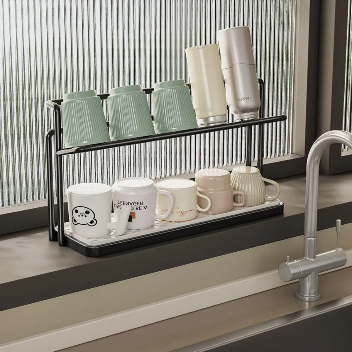 Black two-tier organiser with cups and bottles beside a kitchen sink