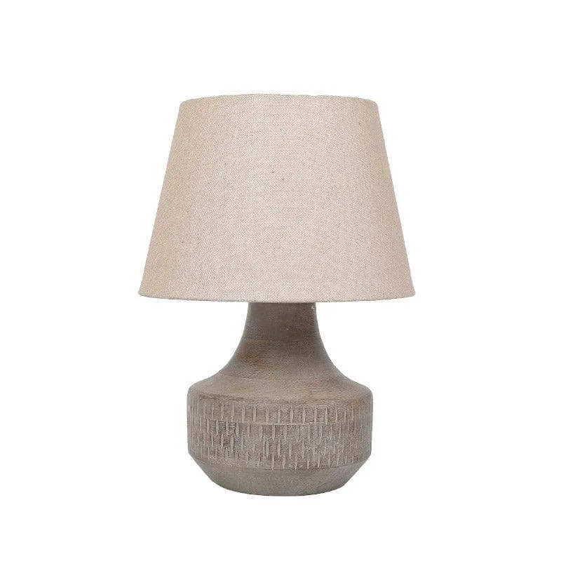 Beige table lamp with tapered fabric shade and rounded textured base on white background.