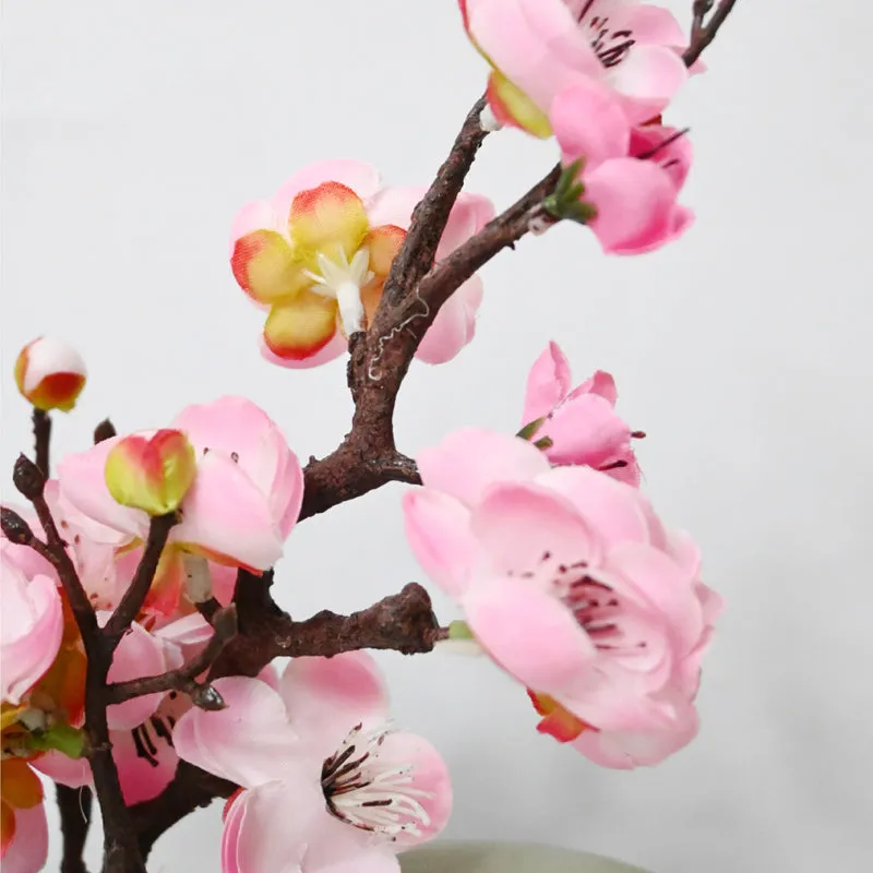 Close-up of pink artificial plum blossoms on a dark textured branch