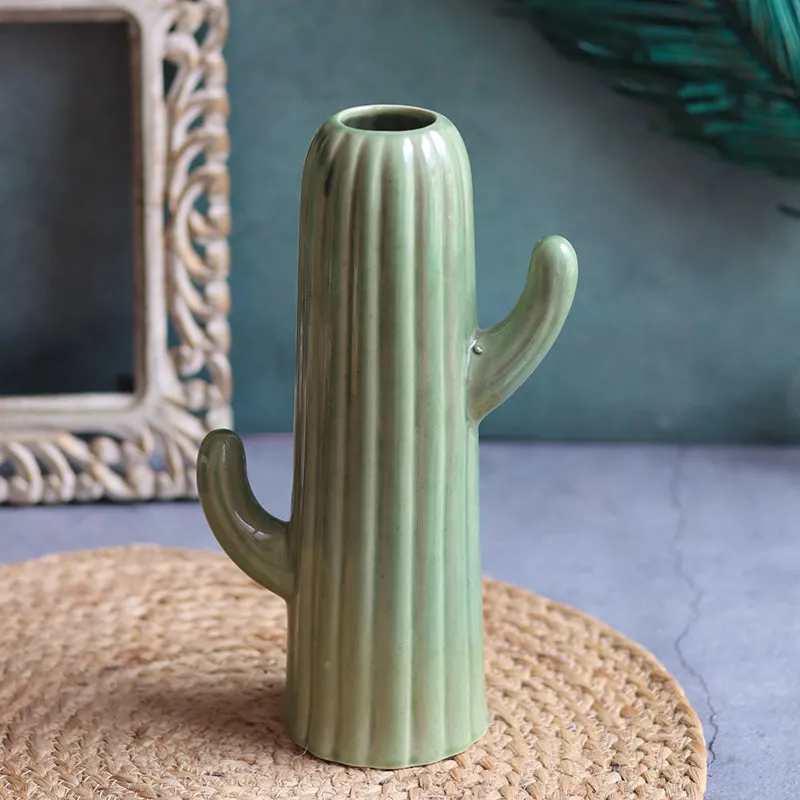 Dark green sculptural cactus-shaped vase on a woven mat