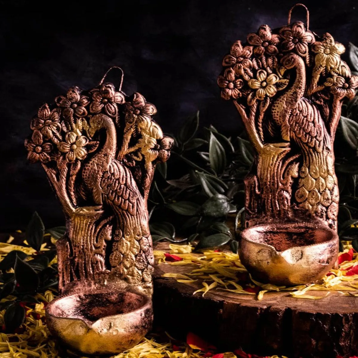Pair of brown peacock diyas with floral detailing arranged on a rustic surface