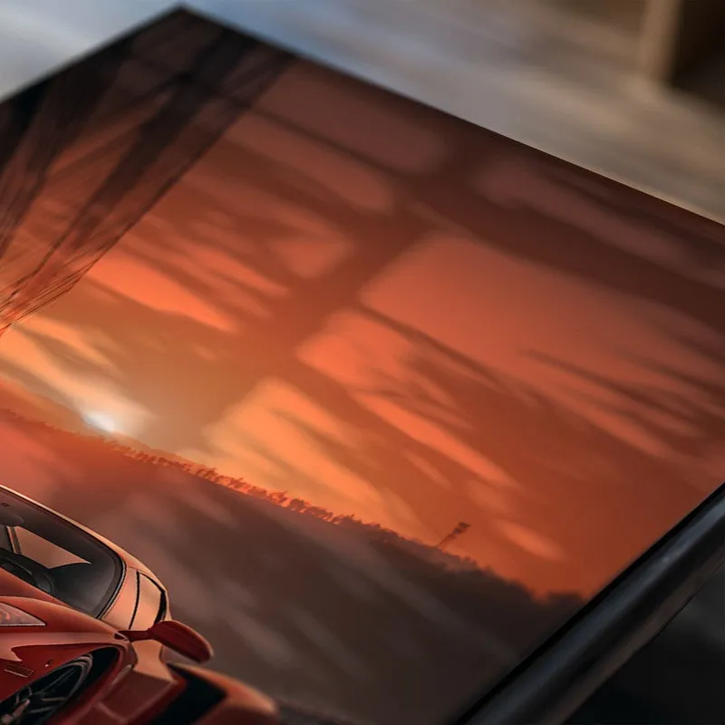 Close-up of glossy wall poster showing a red car at sunset