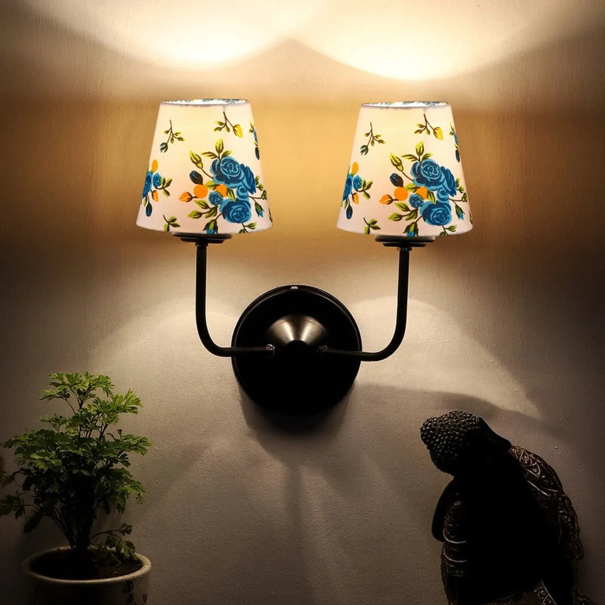 Lit twin wall lamp with two white shades casting upward light