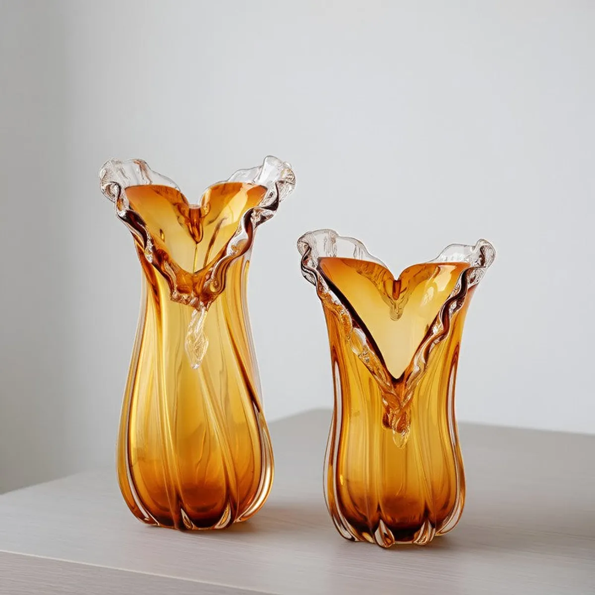 Two gold glass vases in different sizes on a plain surface