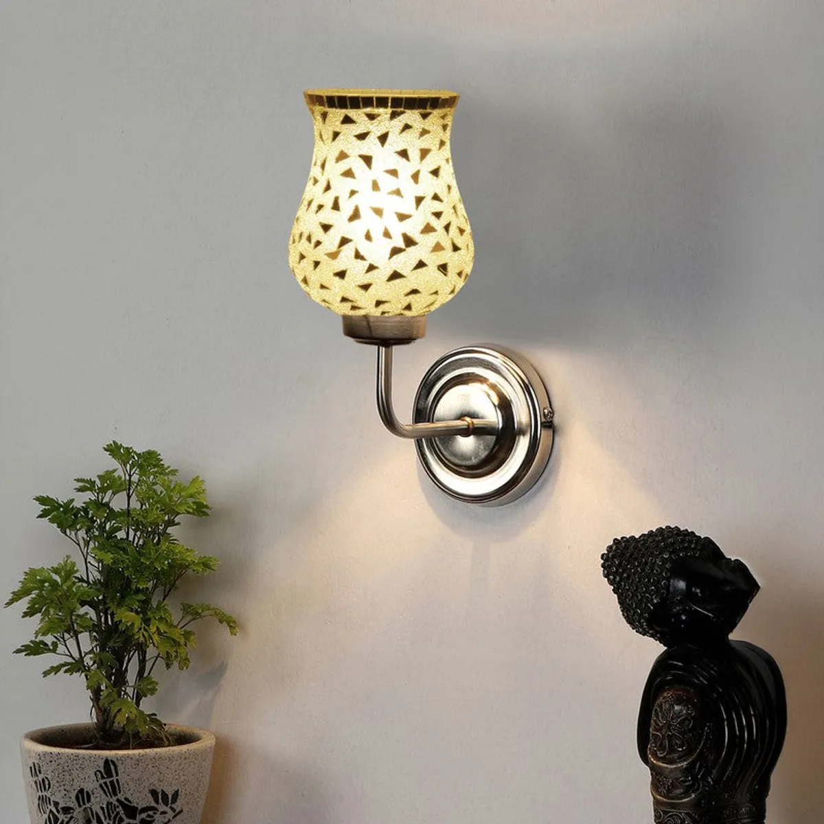 Lit silver mosaic wall lamp with warm glow on white wall