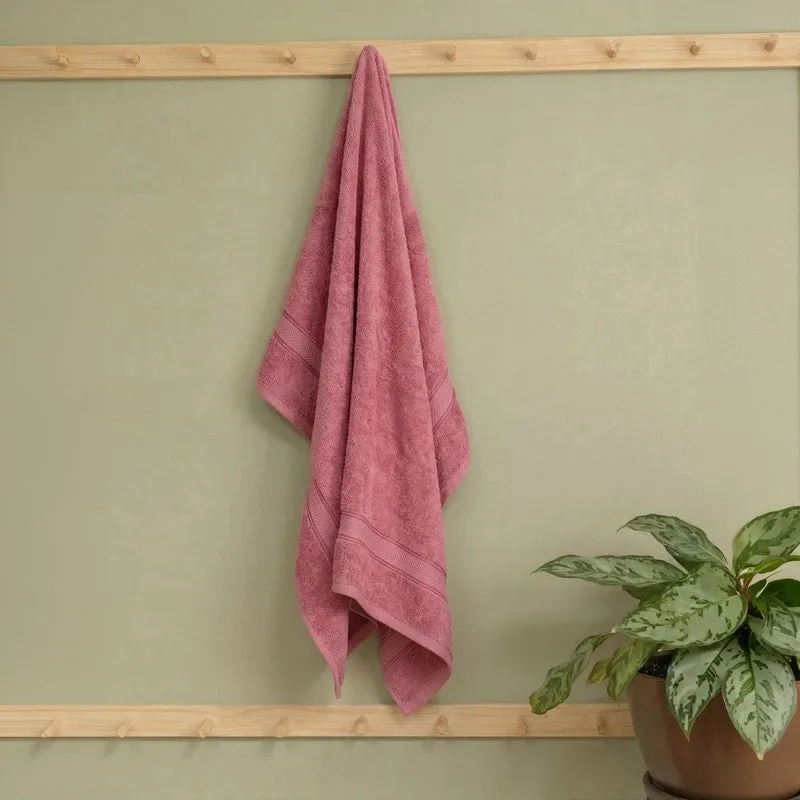 Pink bath towel hanging on a wooden wall rack