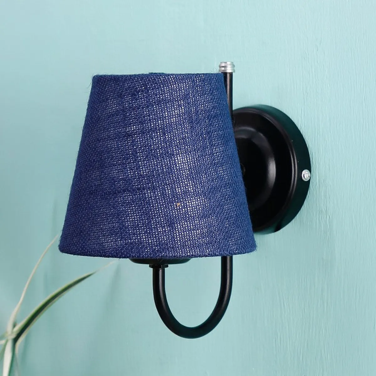 Blue jute wall lamp shown unlit against a light blue wall