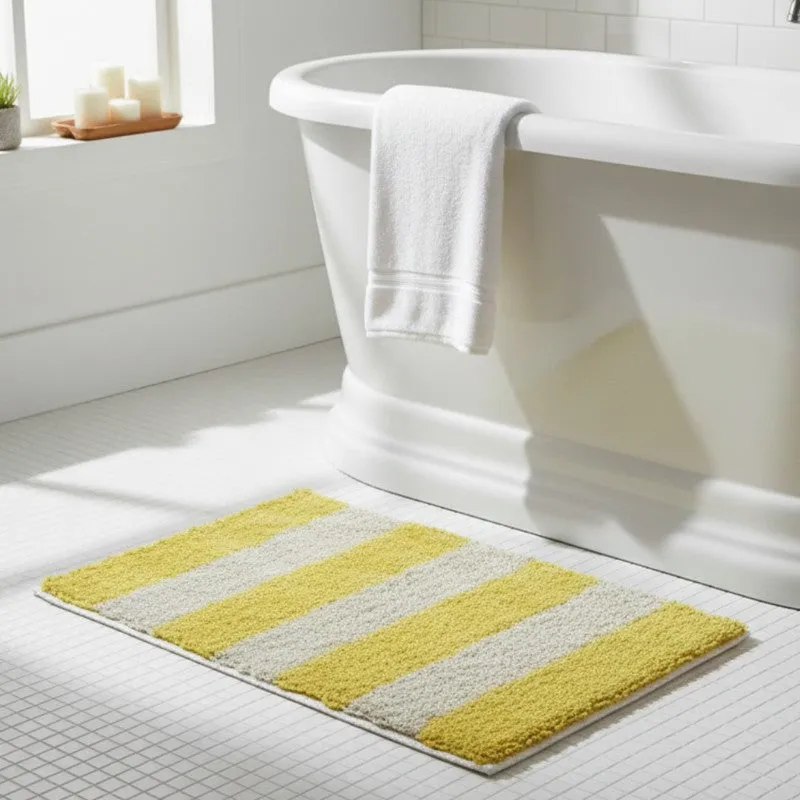 Yellow and white striped bath mat beside a white bathtub
