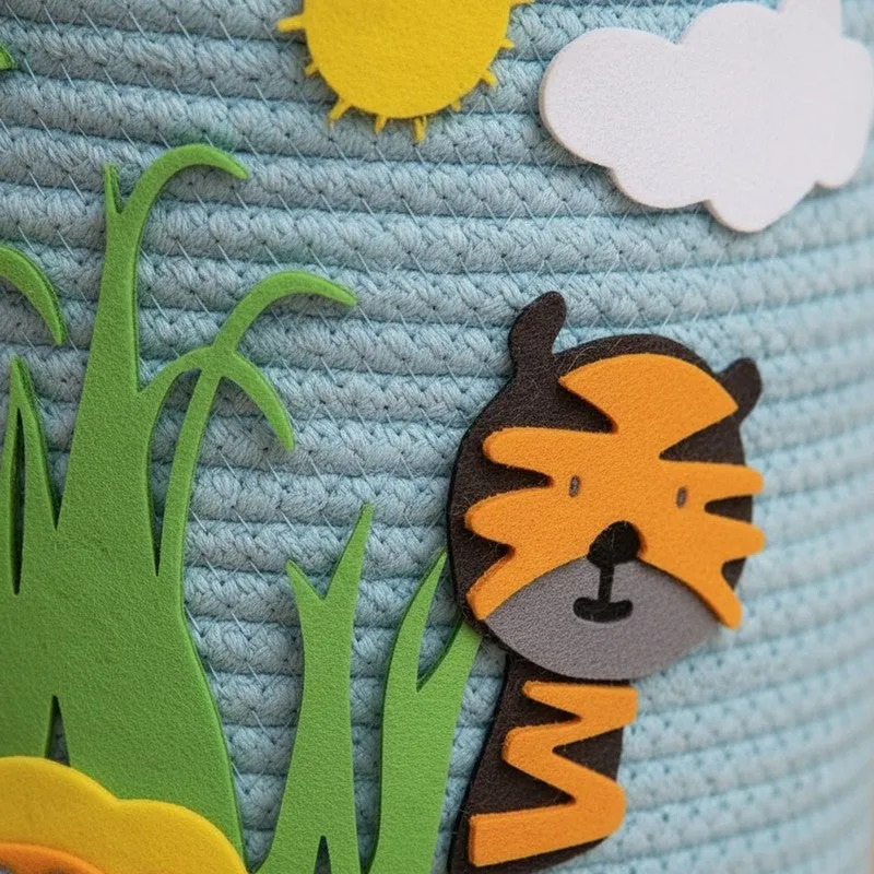 Close-up of tiger appliqué on blue textured basket with grass and cloud motifs