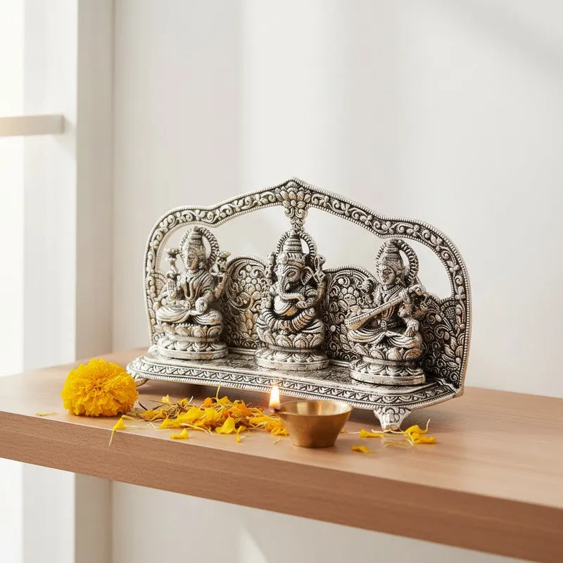 Silver-toned Lakshmi Ganesha Saraswati metal idol on a wooden shelf