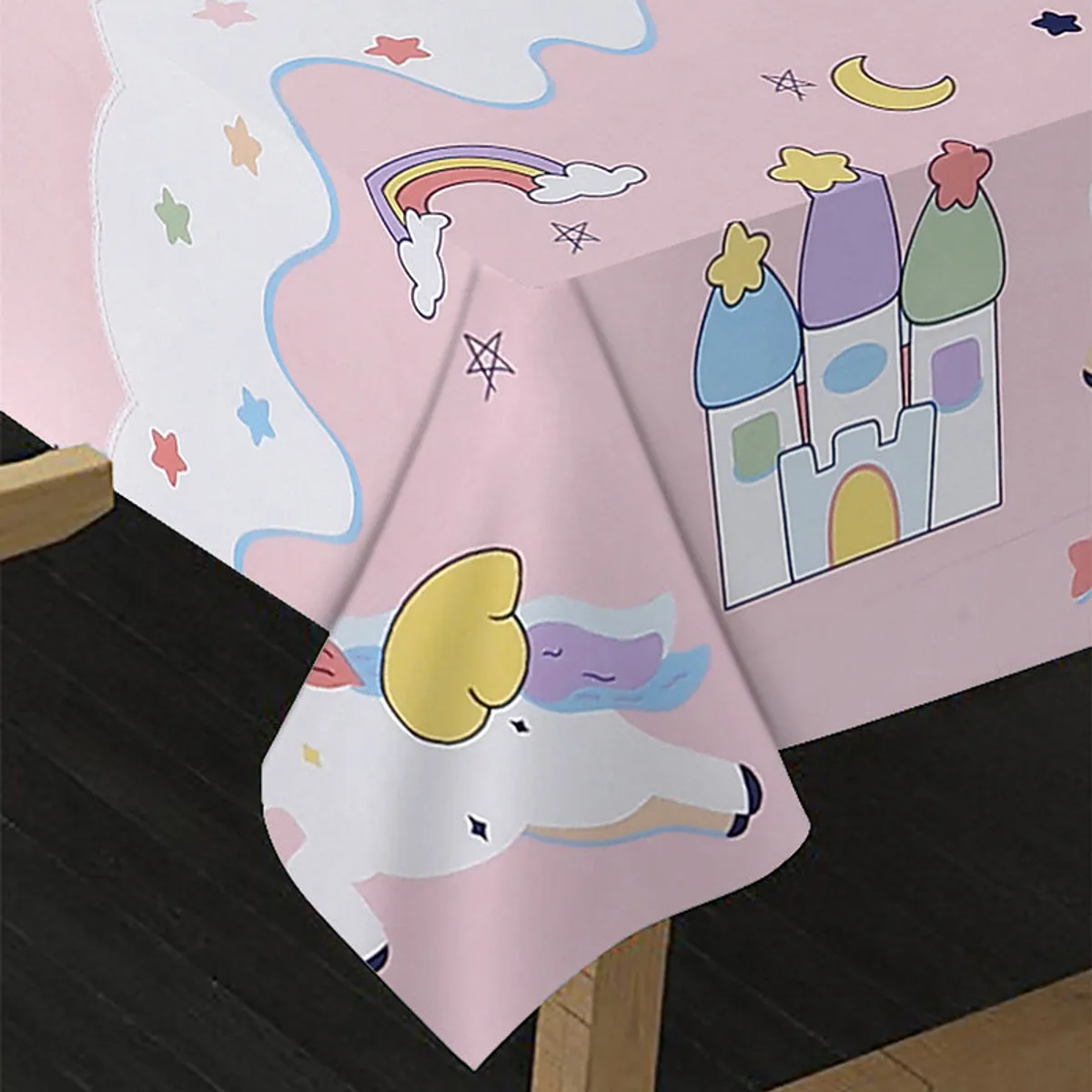 Close-up of the pink table cover showing a unicorn, rainbow and castle print