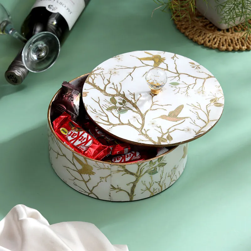 White round storage box with decorative bird motifs, shown open with chocolates
