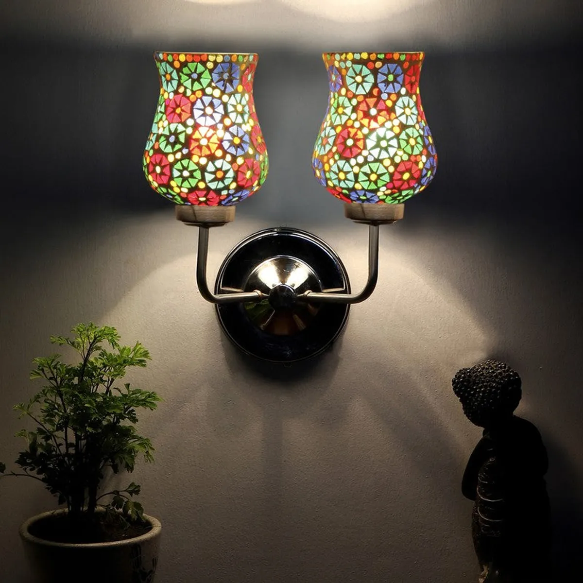 Dual mosaic wall lamp glowing warmly against a dark wall