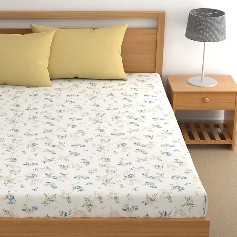 Close view of white floral bedsheet spread on a wooden bed