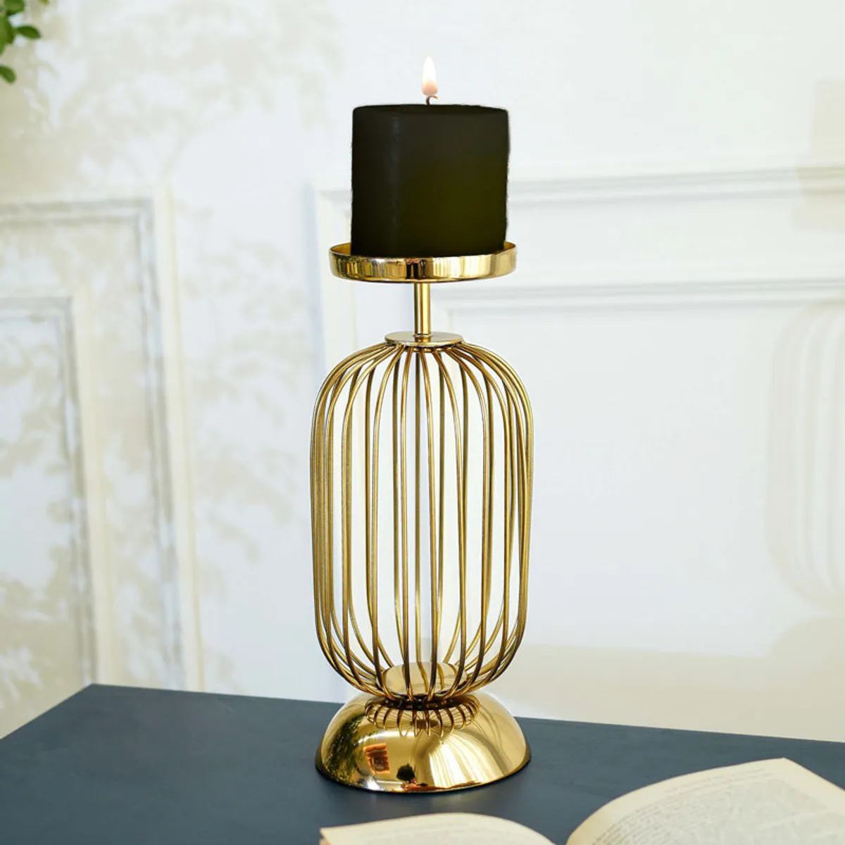 Gold candle holder displaying a black candle against a light wall