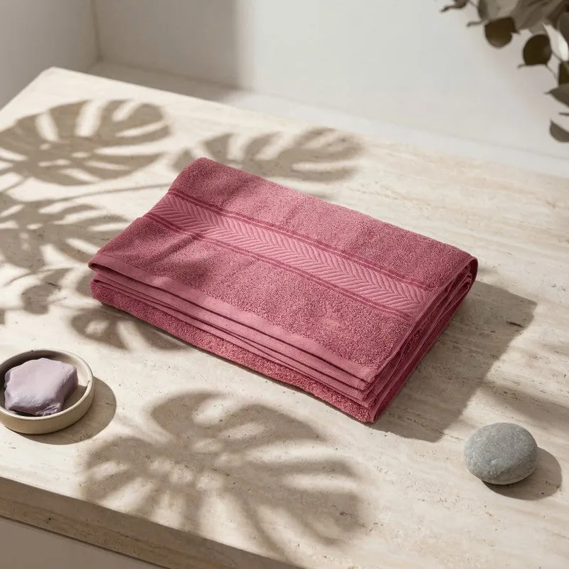 Folded pink bath towel on a light surface