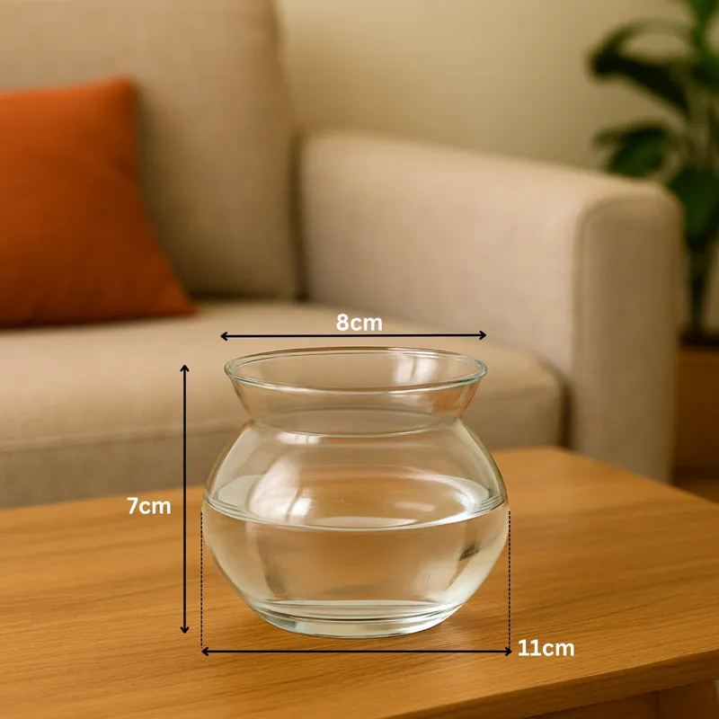 Empty clear glass vase placed on a wooden table in a living room.