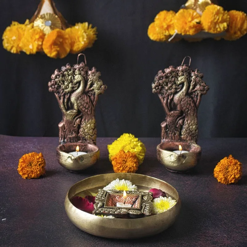 Two peacock hanging diyas displayed with marigold flowers and a decorative tray