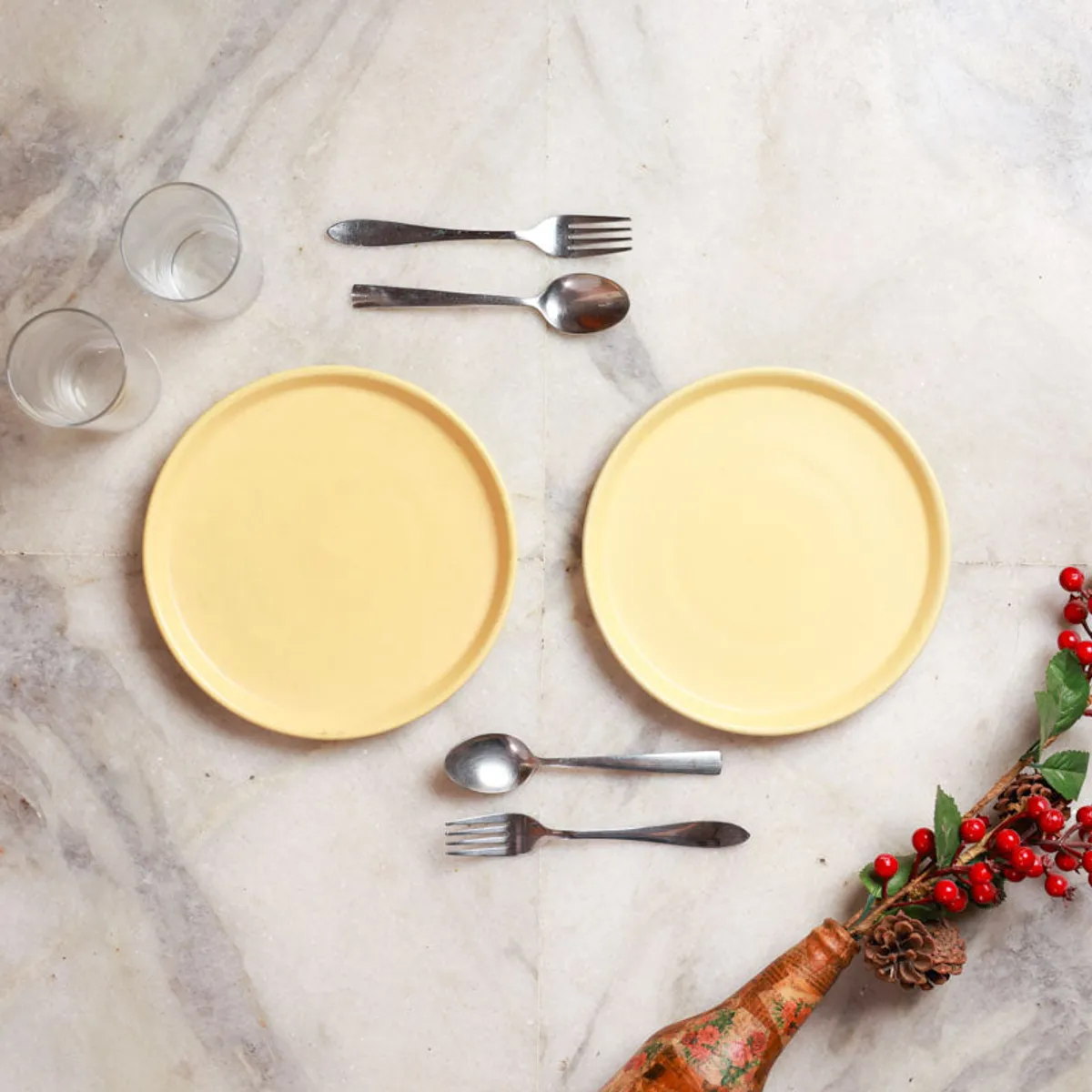 Two yellow round plates arranged with glasses and cutlery