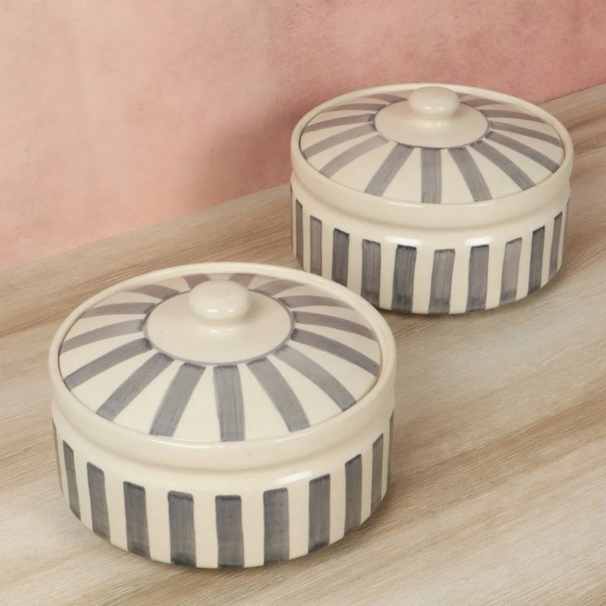 Two grey and white round serving bowls with striped lids shown from above