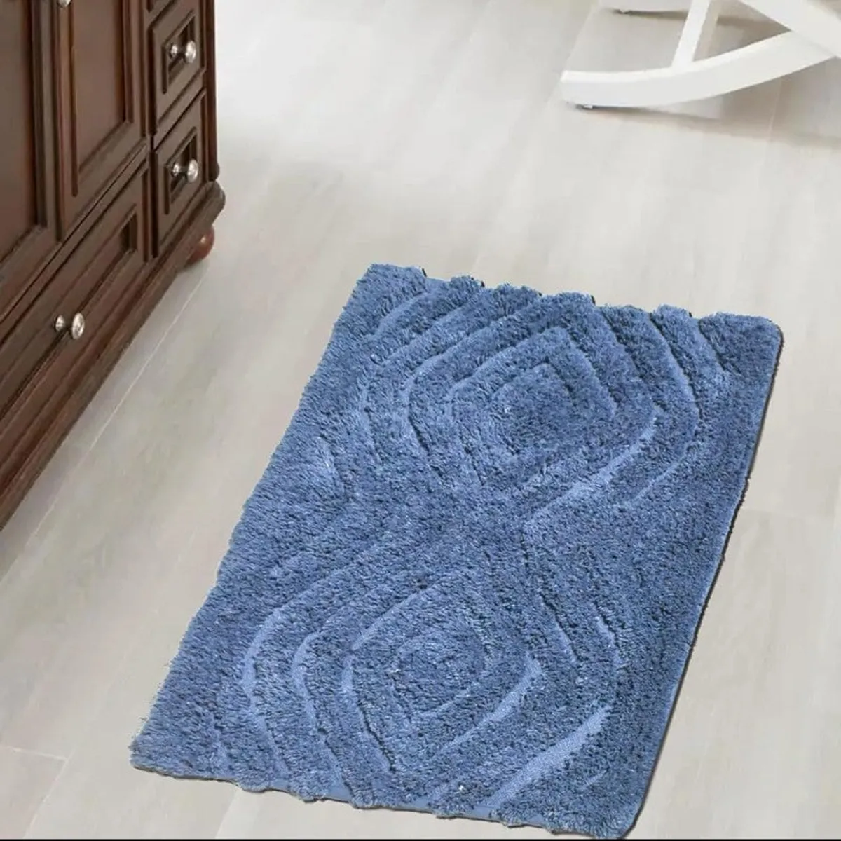 Blue rectangular bath mat shown on a light floor with raised geometric pattern