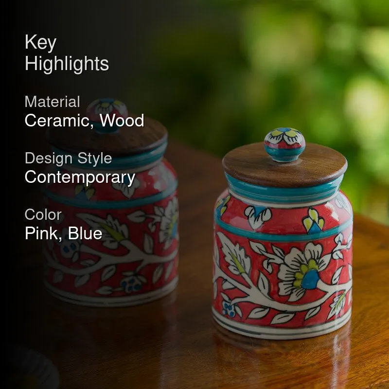 Two floral ceramic jars with wooden lids styled on a tabletop.