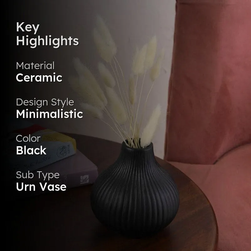 Black ribbed vase with dried stems on a side table