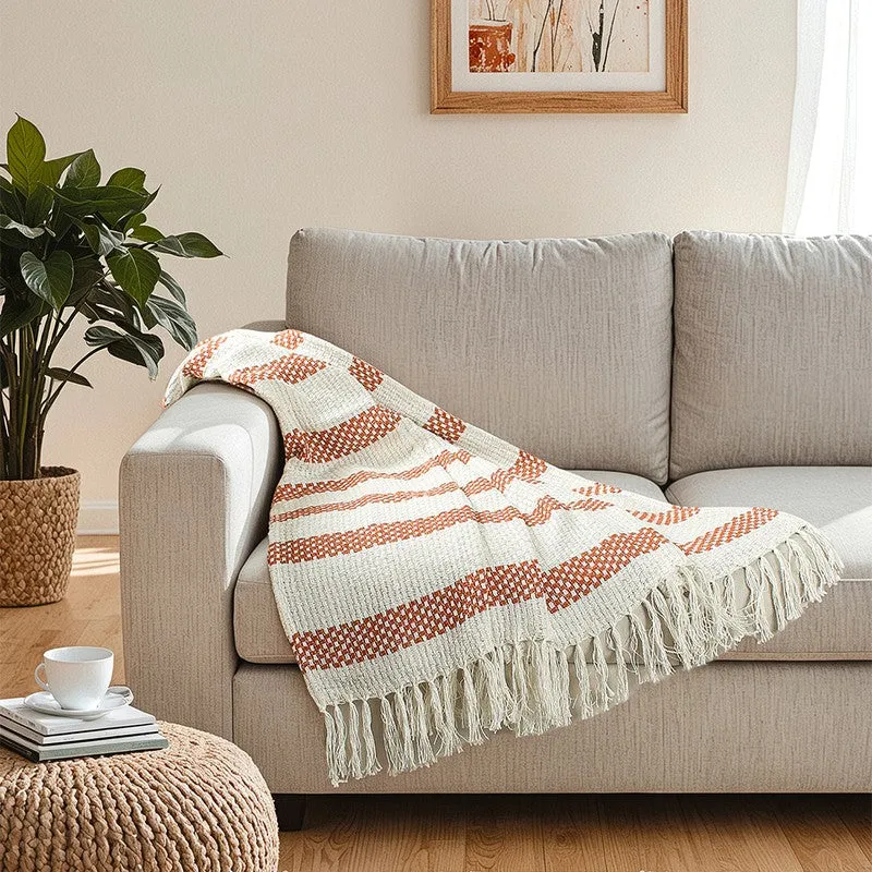 Orange and cream patterned throw spread across a light sofa