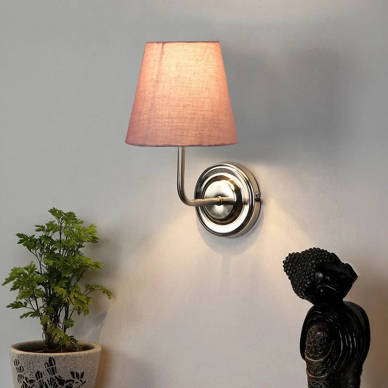 Lit dusty pink wall lamp with steel base on a white wall