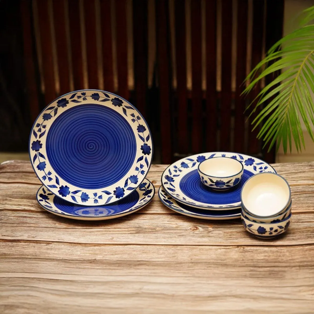 Blue and white floral ceramic plates and bowls arranged on a wooden table