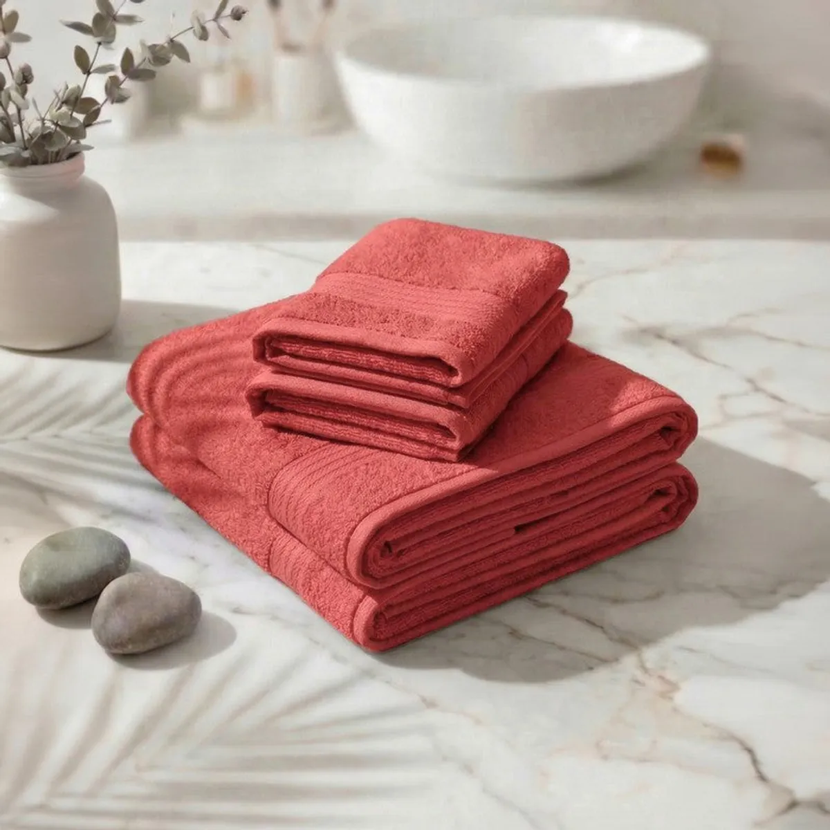 Stacked peach bath and hand towels on a marble surface