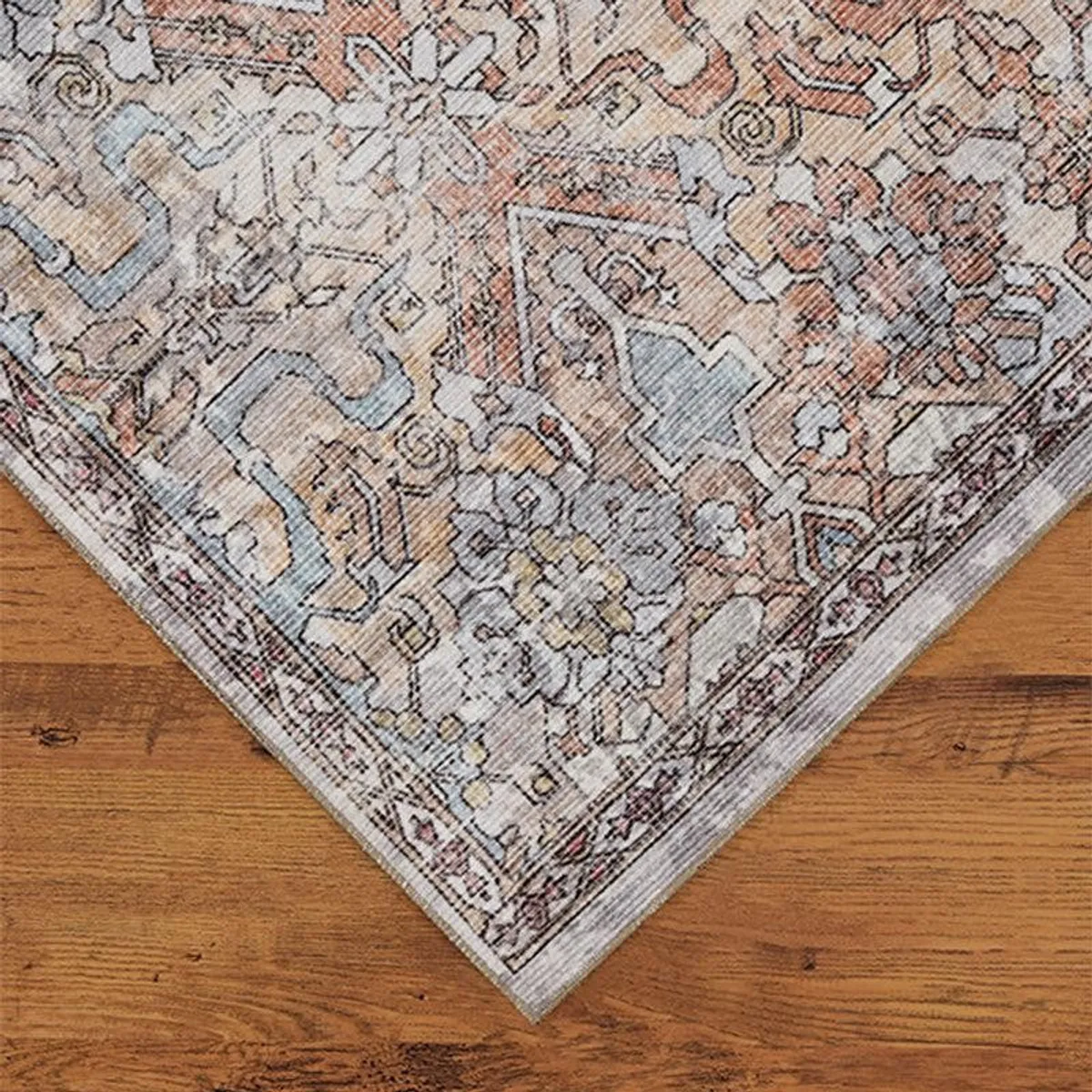 Corner detail of beige carpet with soft blue and peach ethnic motifs