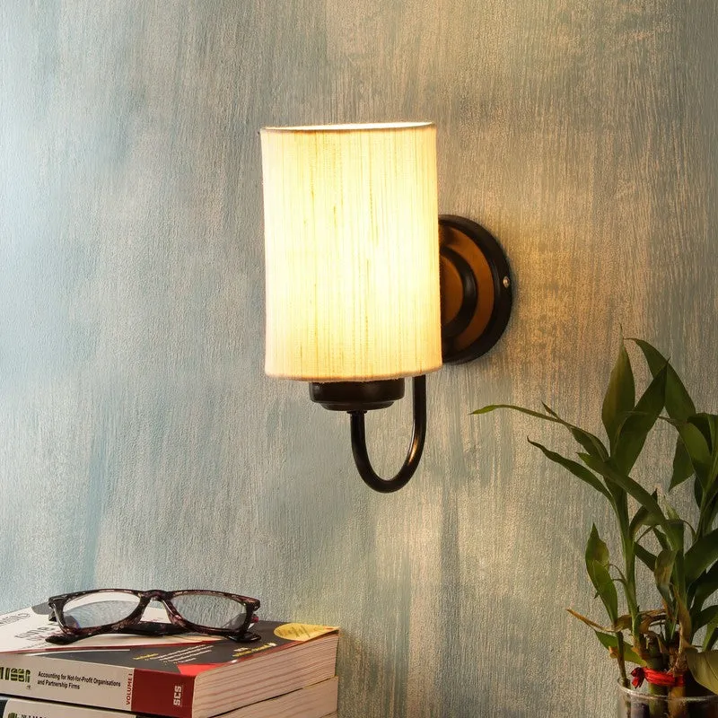 Lit beige cotton wall lamp with black iron base on a textured blue wall