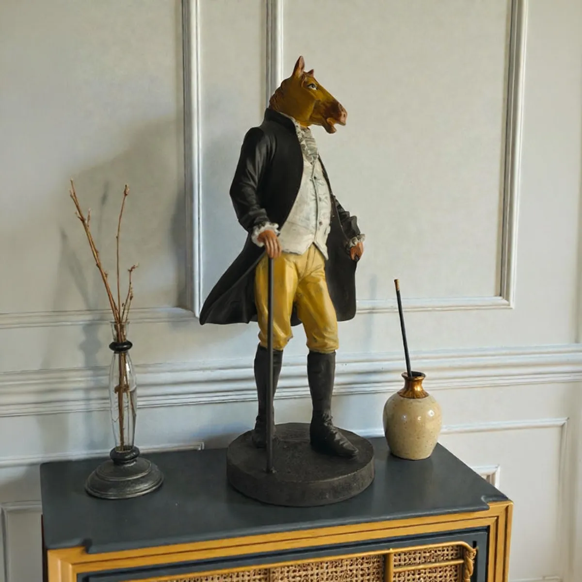 Horse-headed gentleman figurine on a cabinet with decorative vases
