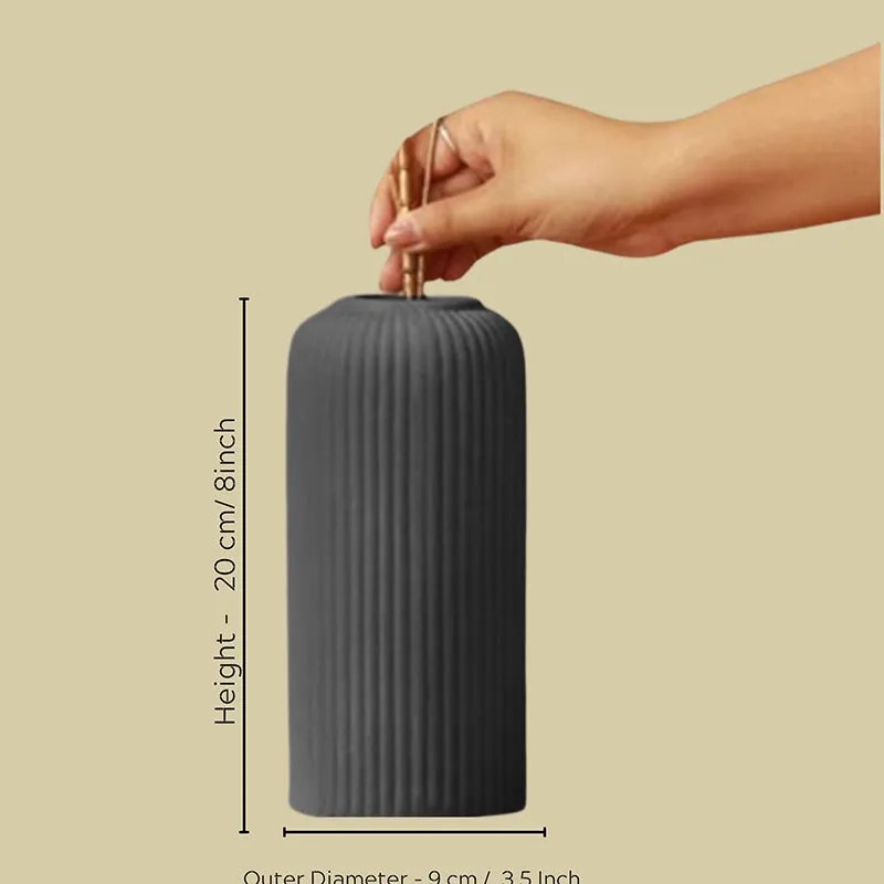 Hand placing stems into a black ribbed vase with dimension markers.