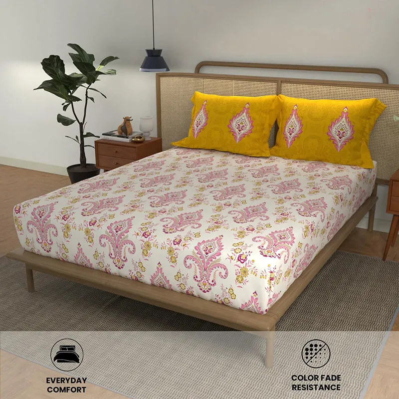 Yellow and pink printed bedsheet styled on a bed with two matching pillow covers