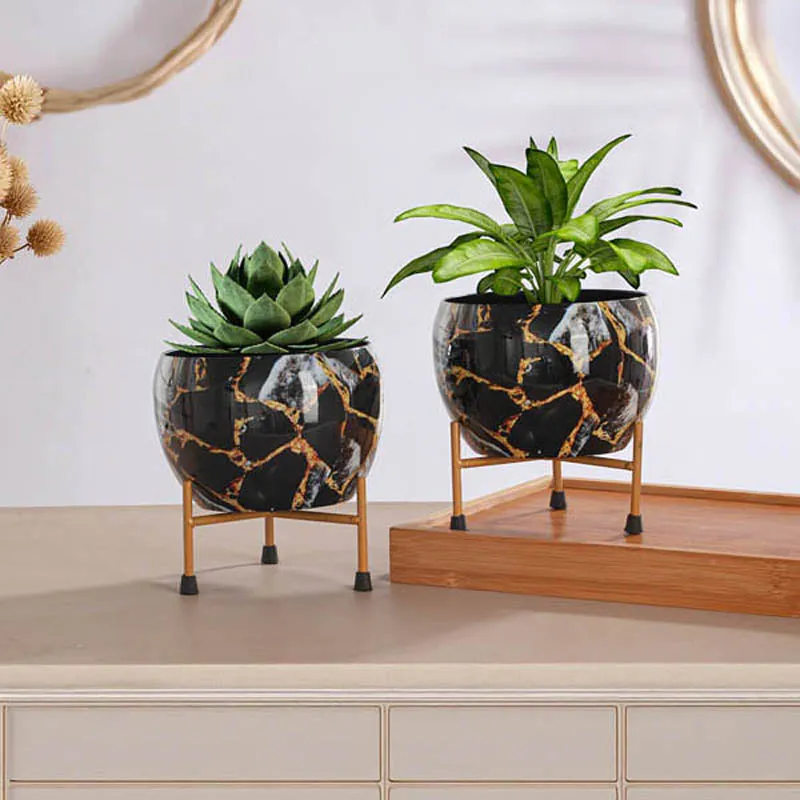 Two small planters with greenery displayed on stands in a styled setting