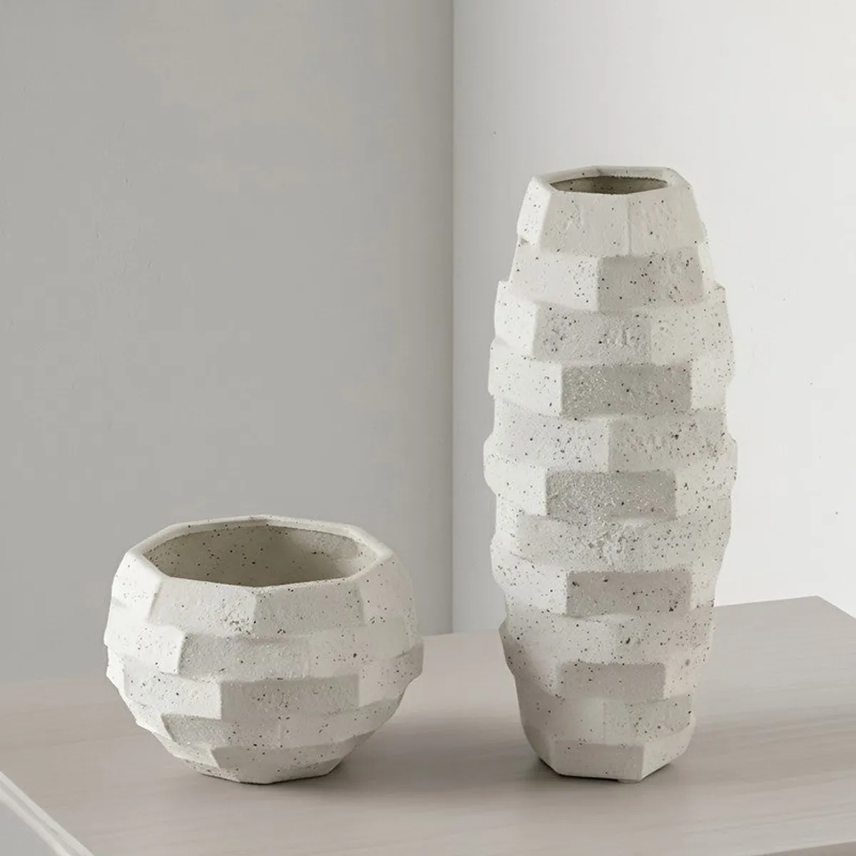 White geometric vase displayed beside a matching bowl-shaped vessel