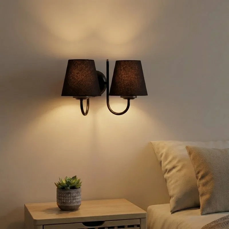 Black twin-shade wall lamp mounted above a bedside table
