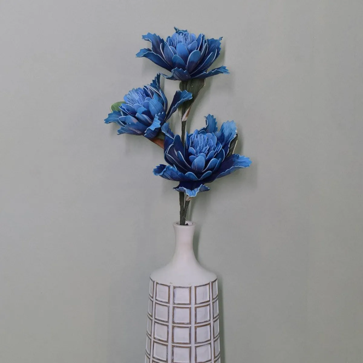 Close view of three blue artificial dahlia flowers and their stems.
