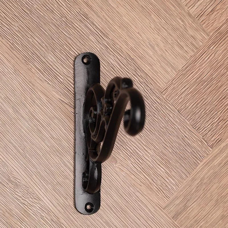 Close side view of the black metal bracket and its decorative raised form.