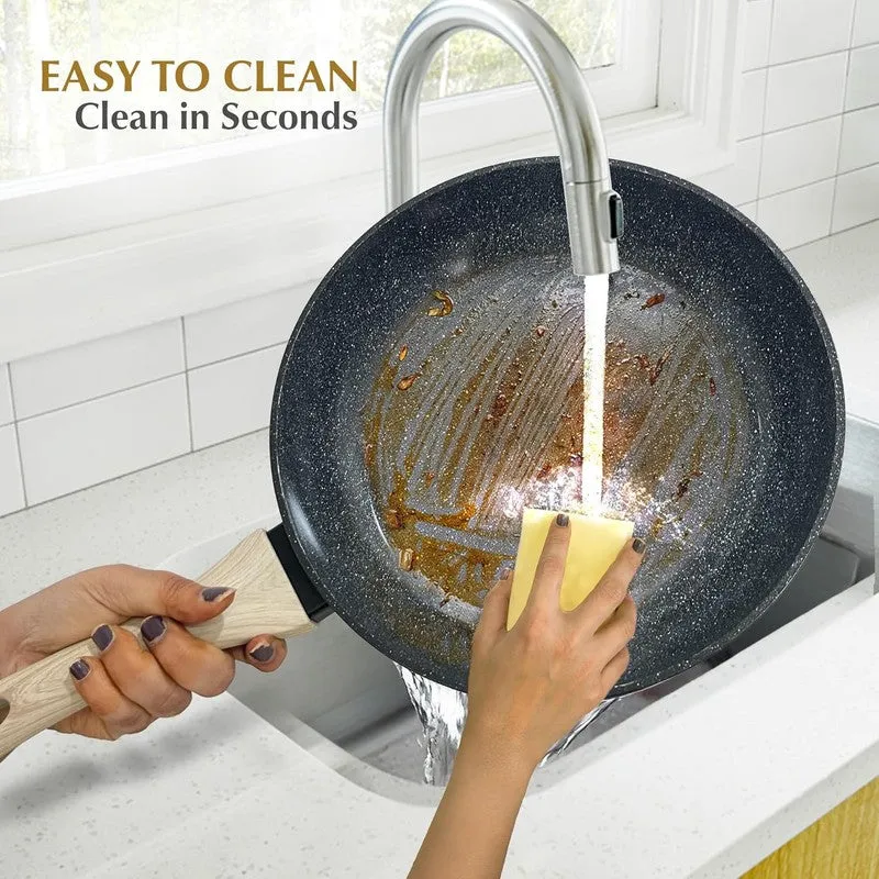 Black frying pan being washed under running water in a kitchen sink