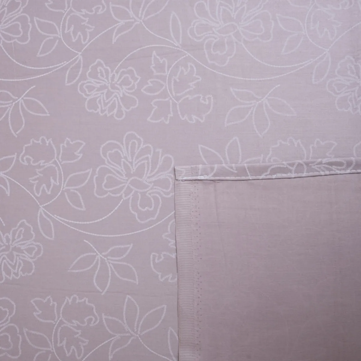 Detailed view of white floral vines on a pink-lavender bedsheet