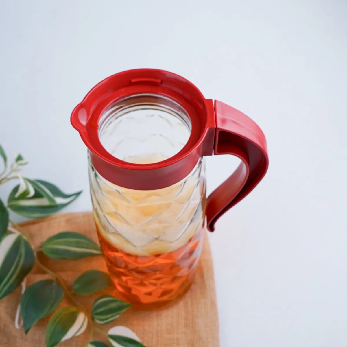 Transparent textured glass jug with red lid and handle, top view