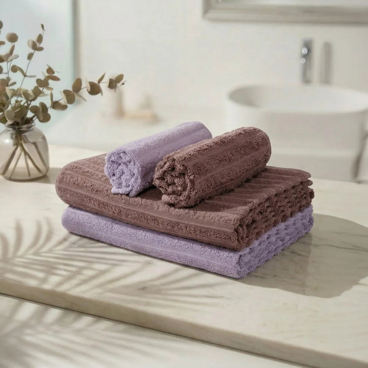 Stacked purple and brown bath and hand towels on a counter